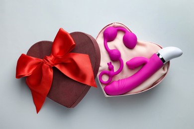 Pink sex toys in heart shaped gift box on white background, flat lay