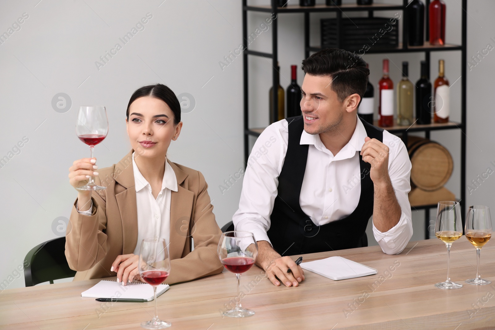 Photo of Sommeliers tasting different sorts of wine at table indoors