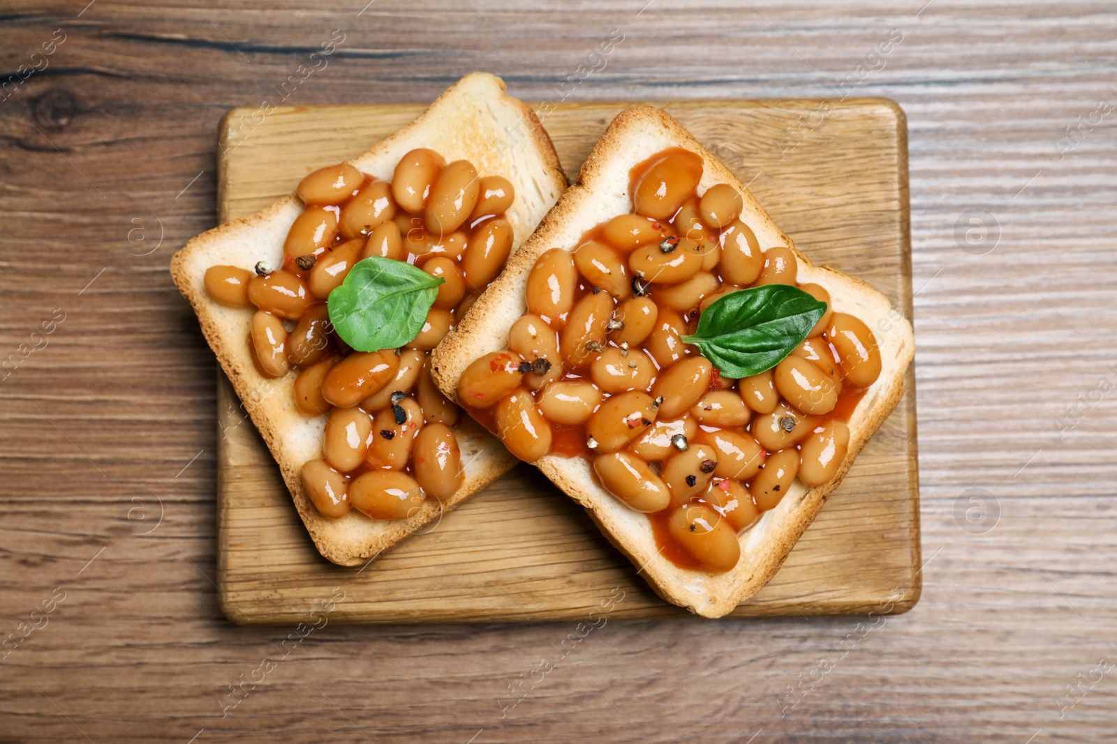Photo of Toasts with delicious canned beans on wooden table, top view