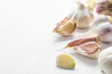 Photo of Fresh organic garlic on white wooden table, closeup. Space for text