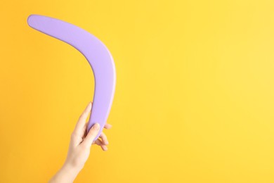 Photo of Woman holding boomerang on yellow background, closeup. Space for text