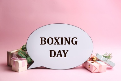 Photo of Speech bubble with phrase BOXING DAY and Christmas decorations on light pink background