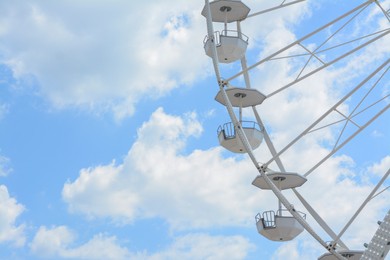 Photo of Large observation wheel against blue cloudy sky, space for text