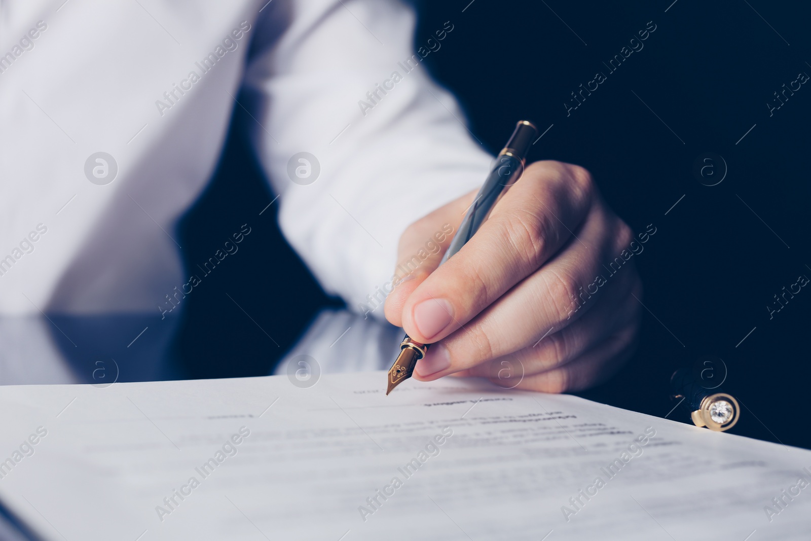 Photo of Notary signing document at black table, closeup