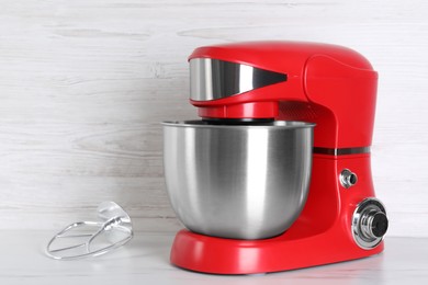 Photo of Modern red stand mixer and flat beater on white marble table, space for text