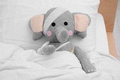 Toy elephant with bandages lying in bed