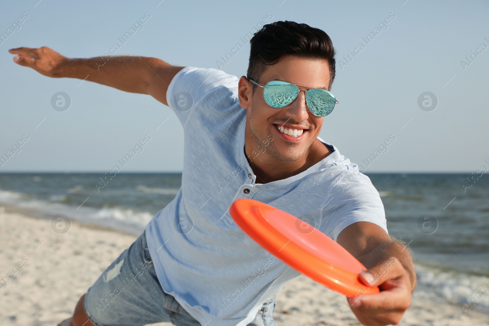 Photo of Happy man throwing flying disk at beach on sunny day