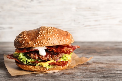 Tasty burger with bacon on wooden table