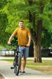 Photo of Handsome man with modern bicycle in park