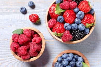 Different fresh ripe berries on light grey wooden table, flat lay