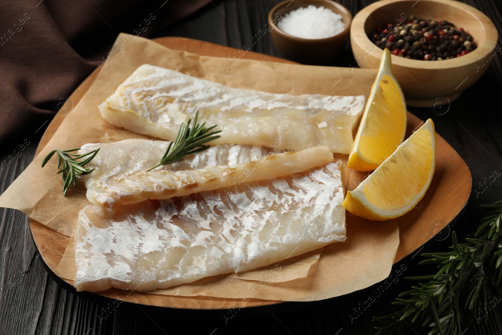 Photo of Fresh raw cod fillets, spices and lemon on wooden table, closeup