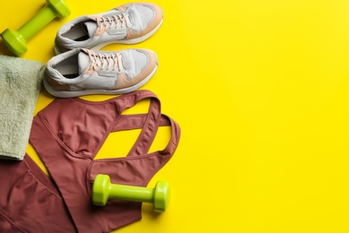 Photo of Flat lay composition with sportswear and equipment on yellow background, space for text. Gym workout