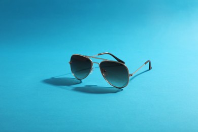 Photo of Sunglasses on light blue background. Stylish accessory