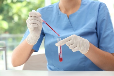 Scientist dripping blood into test tube in laboratory