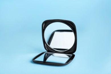 Photo of Stylish cosmetic pocket mirror on light blue background