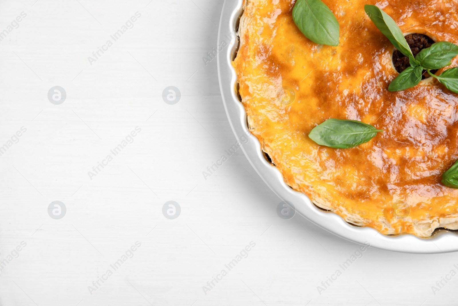 Photo of Delicious pie with minced meat on white wooden table, top view. Space for text