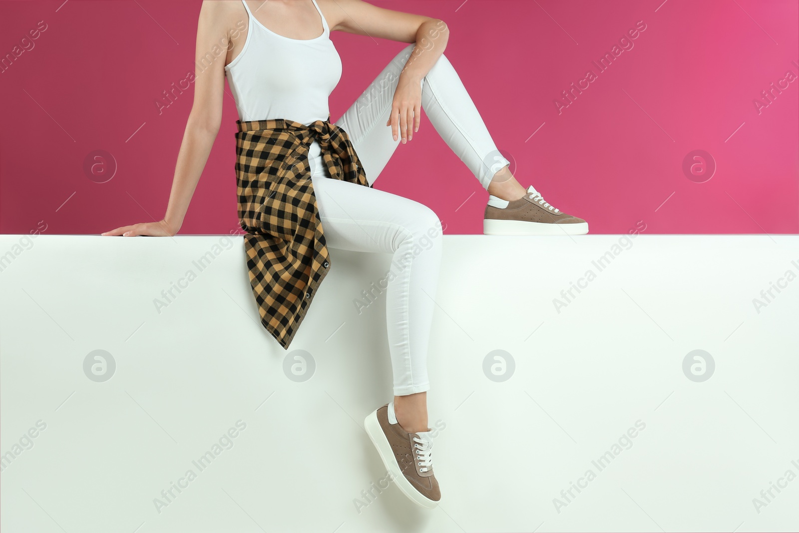 Photo of Woman in stylish shoes sitting on color background, closeup