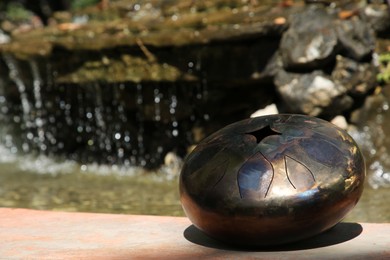 Photo of Steel tongue drum near pond on sunny day, space for text. Percussion musical instrument