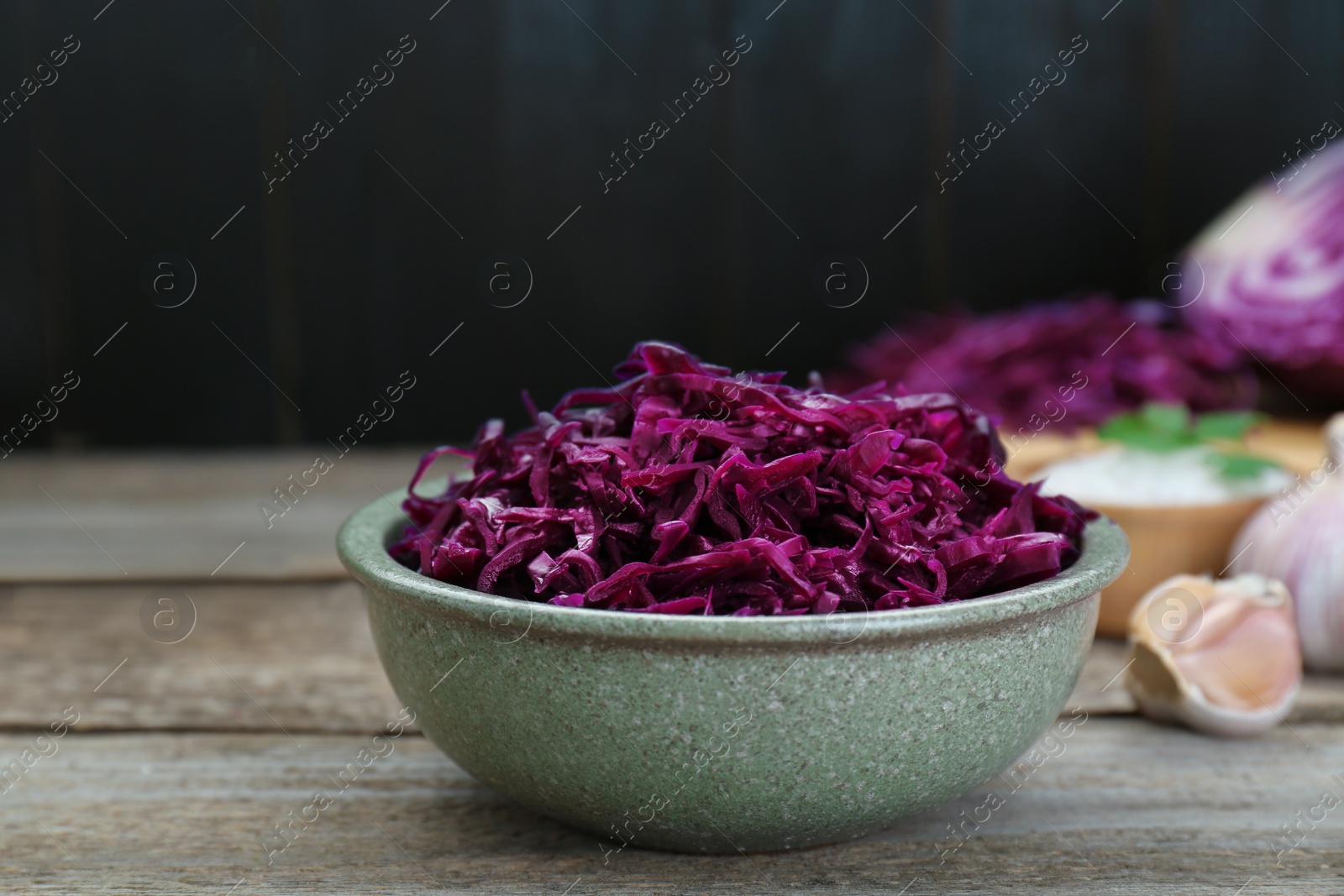 Photo of Tasty red cabbage sauerkraut with parsley on wooden table