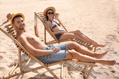 Photo of Young couple relaxing in deck chairs on beach