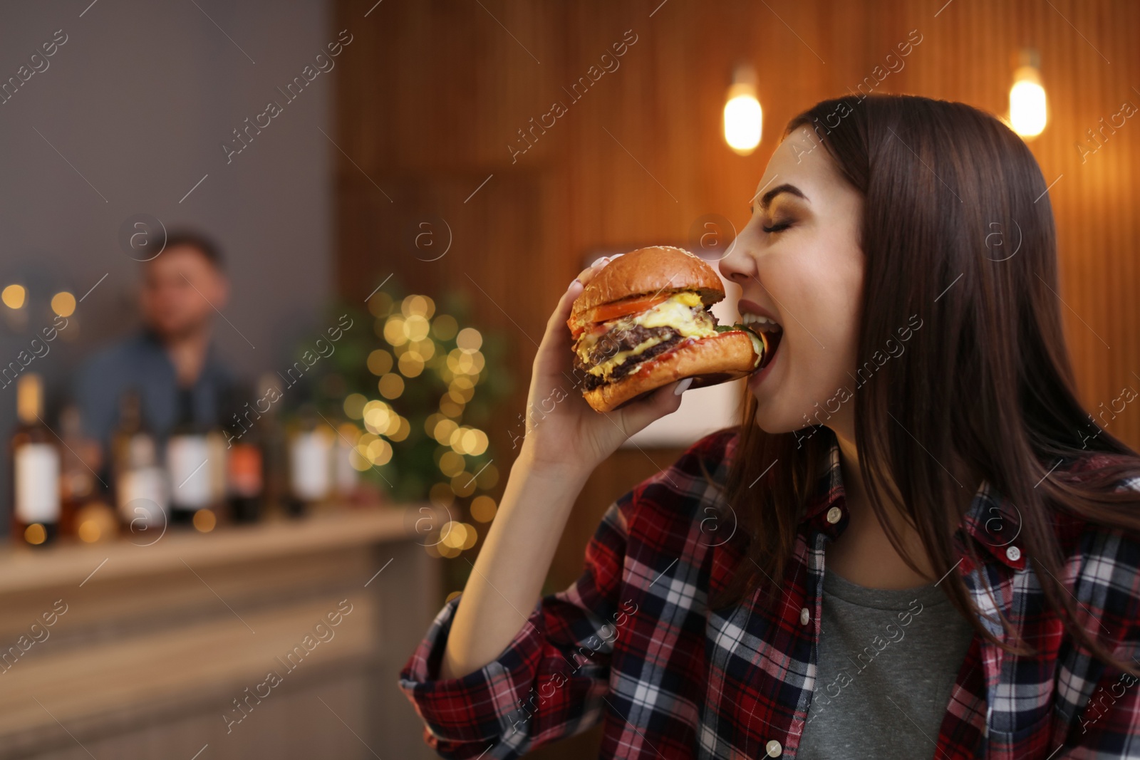 Photo of Young woman eating tasty burger in cafe