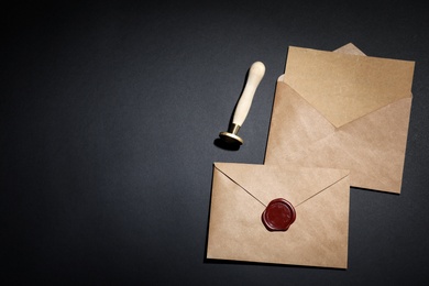 Photo of Envelopes with wax seal and stamp on black background, flat lay. Space for text