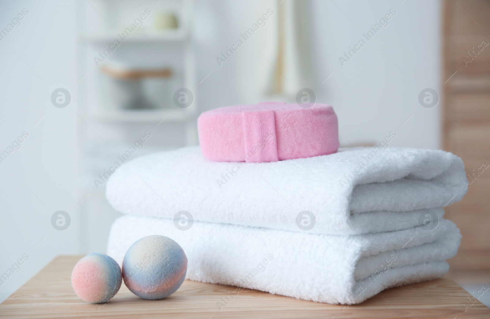 Photo of Clean towels and toiletries on table against blurred background