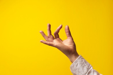 Woman holding something in hand on yellow background, closeup