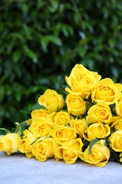 Beautiful bouquet of yellow roses on light table outdoors, space for text