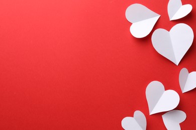 Photo of White paper hearts on red background, flat lay. Space for text