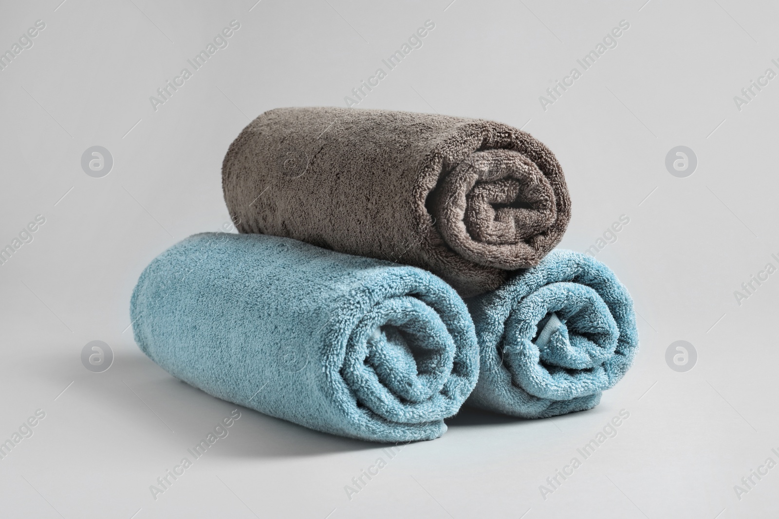 Photo of Fresh soft rolled towels on light background