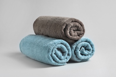 Photo of Fresh soft rolled towels on light background