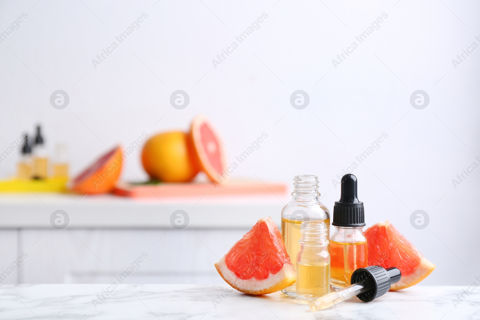 Photo of Bottles of essential oil and grapefruit slices on table. Space for text