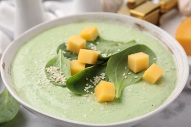 Photo of Delicious spinach cream soup with cheese and sesame seeds in bowl on white marble table, closeup