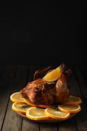 Photo of Baked chicken with orange slices on wooden table. Space for text
