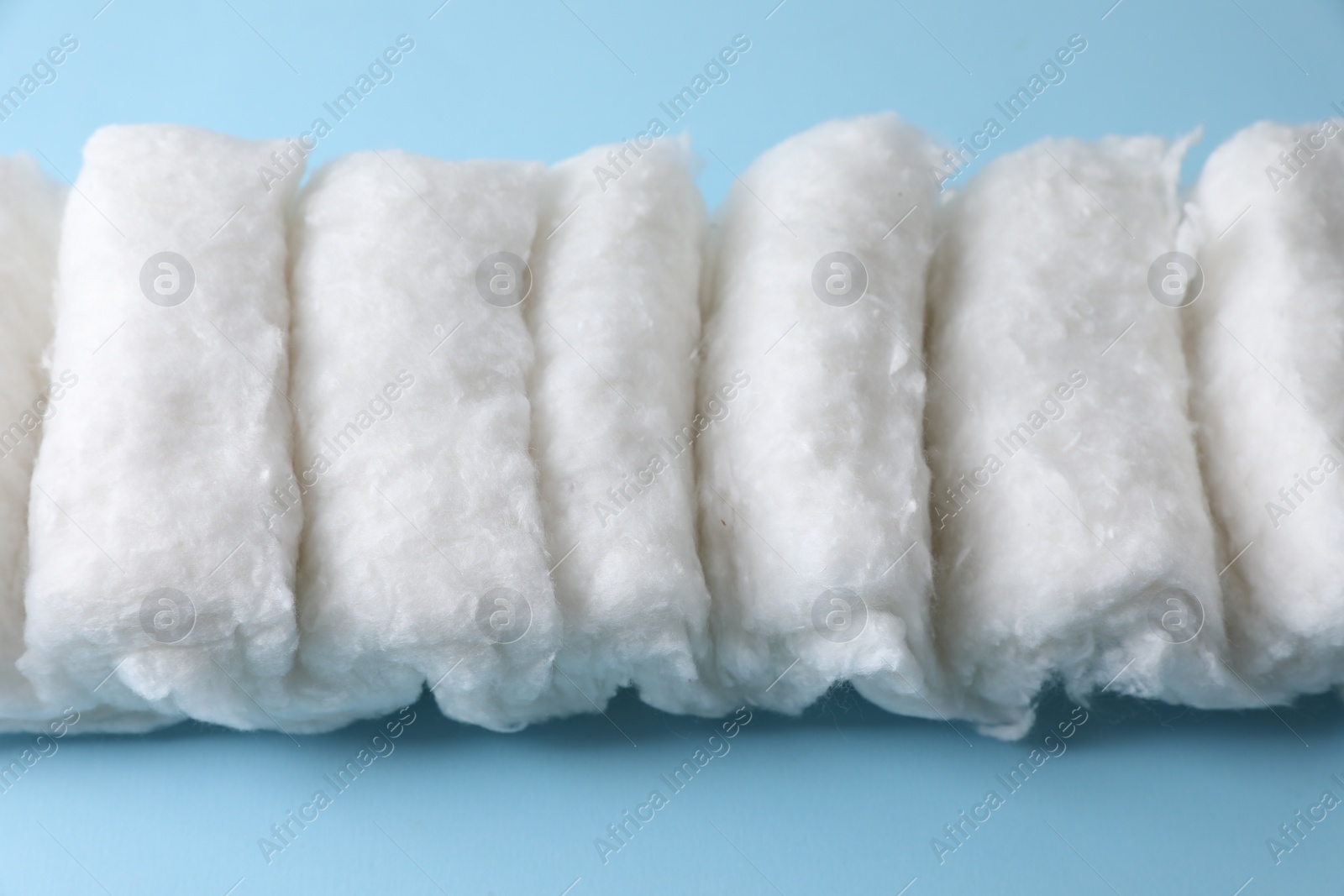 Photo of Soft clean cotton on light blue background, closeup