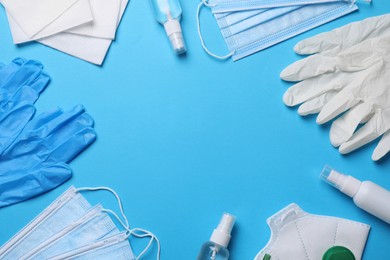 Photo of Hand sanitizers, medical gloves, masks and respirator on light blue background, flat lay. Space for text