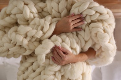 Photo of Woman wrapped with knitted plaid indoors, closeup
