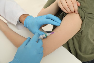 Photo of Doctor giving hepatitis vaccine to patient at table, closeup