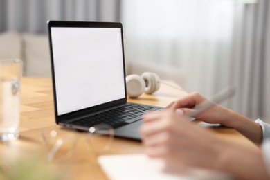 Photo of Young woman watching webinar at table in room, closeup