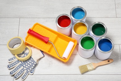 Photo of Cans of paint and decorator tools on wooden floor