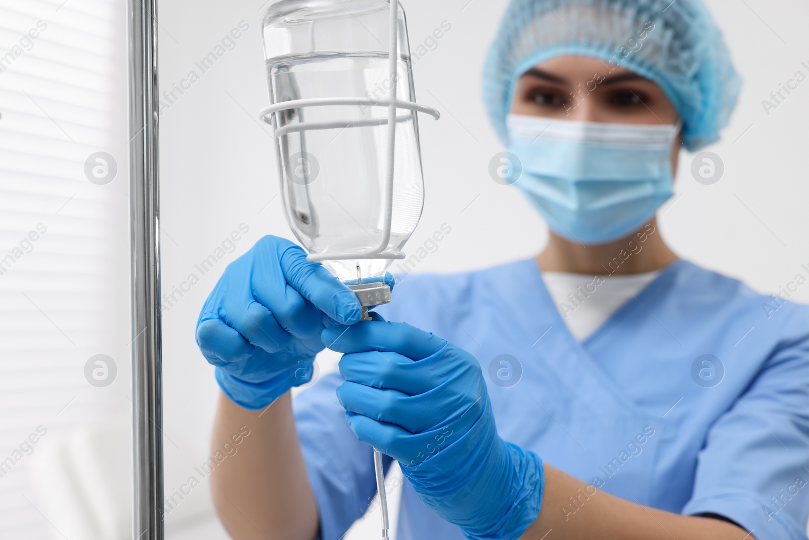 Photo of Nurse setting up IV drip in hospital, selective focus