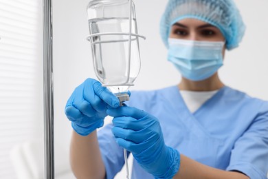 Photo of Nurse setting up IV drip in hospital, selective focus