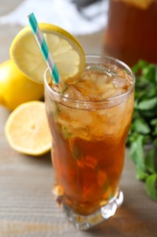 Photo of Delicious iced tea in glass on wooden table, closeup
