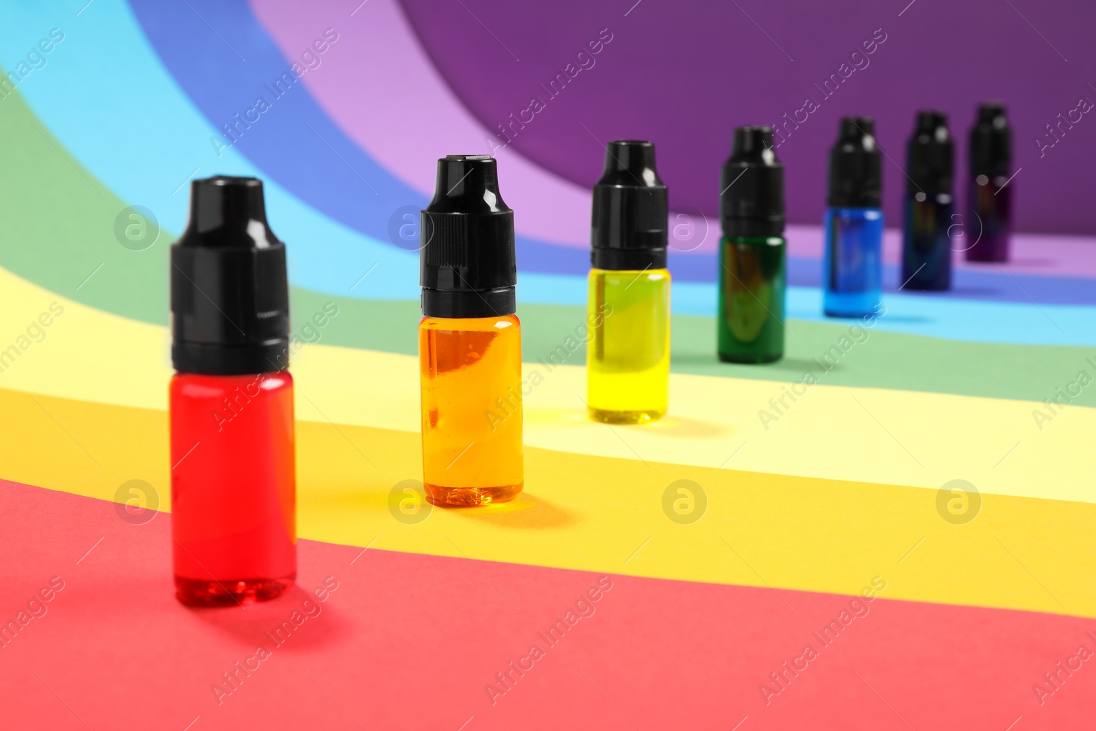 Photo of Bottles with different food coloring on rainbow background