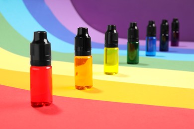 Photo of Bottles with different food coloring on rainbow background