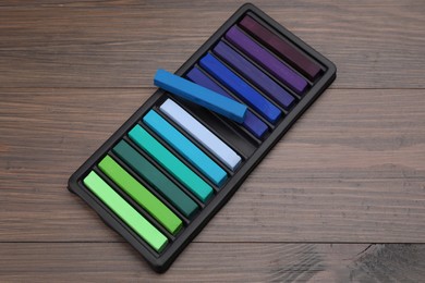 Photo of Colorful pastels in tray on wooden table. Drawing materials