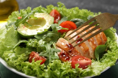 Photo of Eating delicious salad with chicken, cherry tomato and avocado, closeup