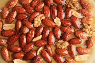 Photo of Tasty almond nuts with honey as background, top view