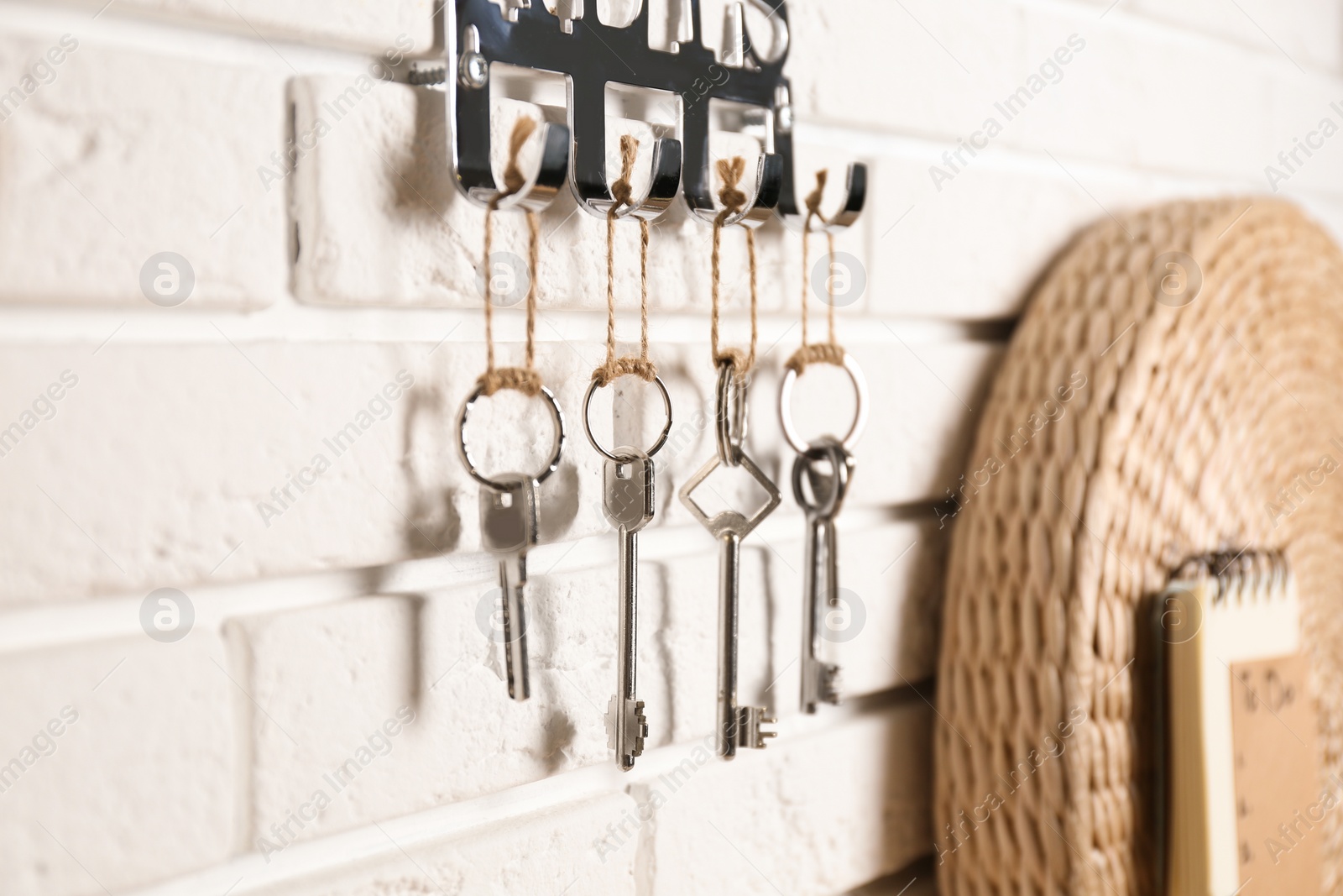 Photo of Metal key holder on white brick wall indoors, closeup